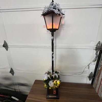 Sale Photo Thumbnail #701: Black lamp post, glowing lantern, snowy top, festive decorated base.