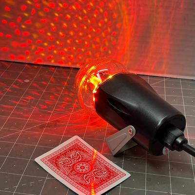 Sale Photo Thumbnail #759: Black cylindrical lamp, textured dome, glowing red reflections.