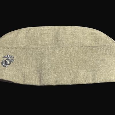 Sale Photo Thumbnail #320: Includes two Korean/Vietnam Era helmets with liners, a USMC flight cap, a USN "Dixie Cup" hat, and a WWII Era Haversack. Total of five pieces. Age related wear. [JP]