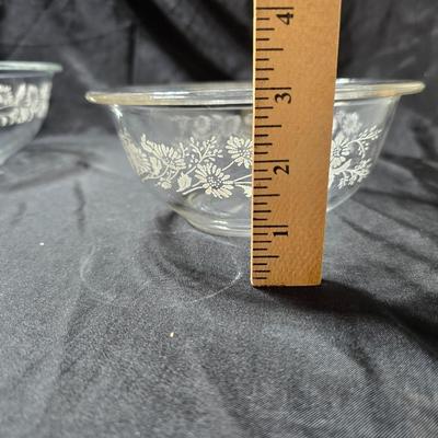 Three vintage Pyrex clear glass nesting mixing bowls in the "Colonial Mist" or "White Lace" pattern.