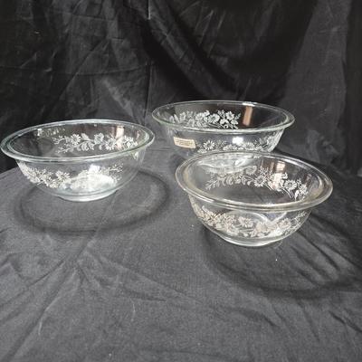 Three vintage Pyrex clear glass nesting mixing bowls in the "Colonial Mist" or "White Lace" pattern.