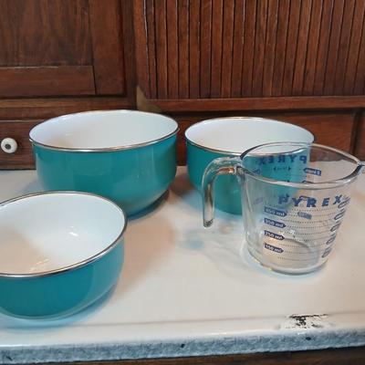 Three nesting enamel mixing bowls and a glass Pyrex measuring cup