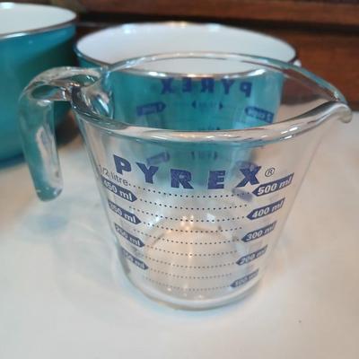 Three nesting enamel mixing bowls and a glass Pyrex measuring cup