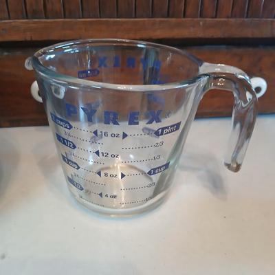 Three nesting enamel mixing bowls and a glass Pyrex measuring cup