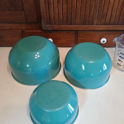 Three nesting enamel mixing bowls and a glass Pyrex measuring cup
