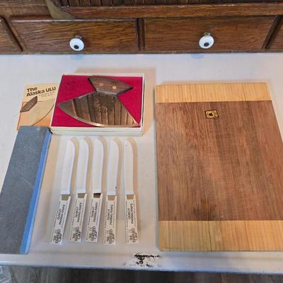 Wooden cutting board with 5 Pampered Chef Quickut Paring Knives and an Alaskan Ulu knife