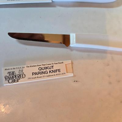 Wooden cutting board with 5 Pampered Chef Quickut Paring Knives and an Alaskan Ulu knife