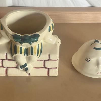 Sale Photo Thumbnail #3: Charming vintage Humpty Dumpty cookie jar, featuring the classic nursery rhyme character sitting on a brick wall. Hand-painted ceramic with soft pastel tones, green bowtie, and striped outfit. Two-piece design with removable head lid.
Perfect for vintage 