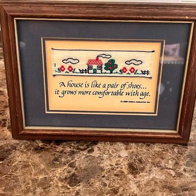 Sale Photo Thumbnail #17: Limited-edition Isidore Industries “Needle Art of the Old World” No. 19, featuring a woven cottage scene and the quote:
“A house is like a pair of shoes… it grows more comfortable with age.”
Authentic hand-woven piece mounted under glass in its 