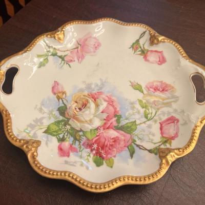 Sale Photo Thumbnail #26: Exquisite antique Limoges France porcelain cake plate, hand-decorated with pink and white roses over a soft sky-blue background. Features ornate pierced handles, scalloped rim, and raised gold beading around the border.
Dual marks include T&V Limoges Fran