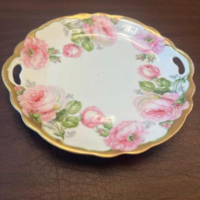 Sale Photo Thumbnail #61: Elegant vintage porcelain handled plate from Bavaria, featuring delicate pink roses and gold edging. The floral transfer pattern is typical of early 1900s Bavarian export porcelain, often produced by makers such as Zeh, Scherzer & Co. or R.S. Bavaria.
Det