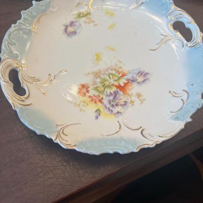 Sale Photo Thumbnail #65: Beautiful trio of early 20th-century European porcelain display plates, each showcasing hand-painted or transfer-decorated artistry and fine embossed detailing.
Included:
1.	Game Bird Plate – embossed rim with scalloped edges, featuring a detailed pheas