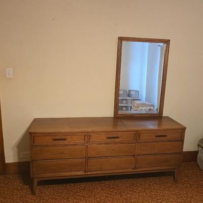 Mid-century modern walnut nine-drawer lowboy dresser by Dixie Furniture Co. with a matching mirror.