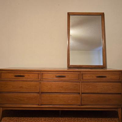 Mid-century modern walnut nine-drawer lowboy dresser by Dixie Furniture Co. with a matching mirror.