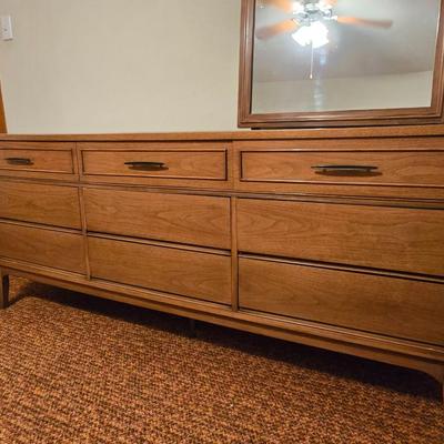 Mid-century modern walnut nine-drawer lowboy dresser by Dixie Furniture Co. with a matching mirror.