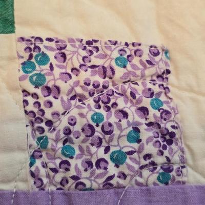 Handmade patchwork quilt featuring a scrappy nine-patch block design and a light purple border. Postage Stamp quilt Irish Chain pattern