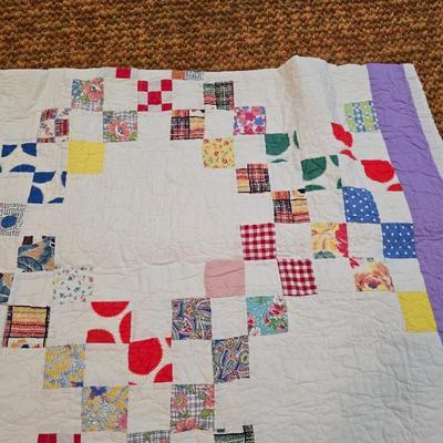 Handmade patchwork quilt featuring a scrappy nine-patch block design and a light purple border. Postage Stamp quilt Irish Chain pattern