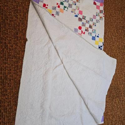 Handmade patchwork quilt featuring a scrappy nine-patch block design and a light purple border. Postage Stamp quilt Irish Chain pattern