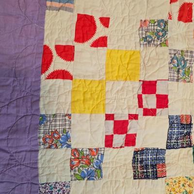 Handmade patchwork quilt featuring a scrappy nine-patch block design and a light purple border. Postage Stamp quilt Irish Chain pattern