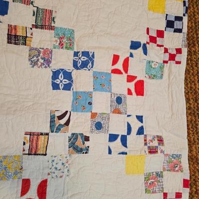 Handmade patchwork quilt featuring a scrappy nine-patch block design and a light purple border. Postage Stamp quilt Irish Chain pattern