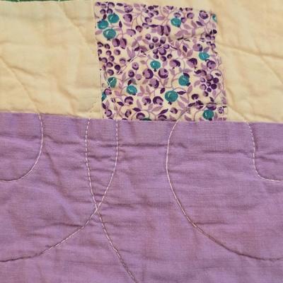 Handmade patchwork quilt featuring a scrappy nine-patch block design and a light purple border. Postage Stamp quilt Irish Chain pattern