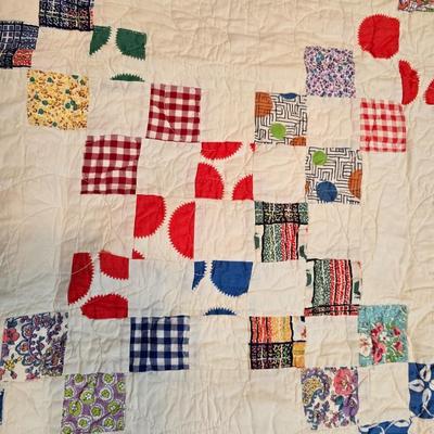 Handmade patchwork quilt featuring a scrappy nine-patch block design and a light purple border. Postage Stamp quilt Irish Chain pattern