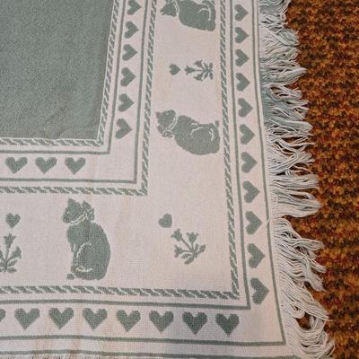 handmade green and white crochet blanket with a leaves pattern and fringed edges with a knitted reverse cat themed throw