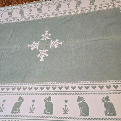 handmade green and white crochet blanket with a leaves pattern and fringed edges with a knitted reverse cat themed throw