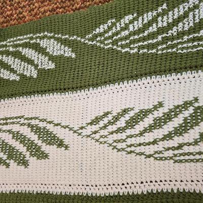 handmade green and white crochet blanket with a leaves pattern and fringed edges with a knitted reverse cat themed throw