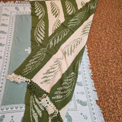 handmade green and white crochet blanket with a leaves pattern and fringed edges with a knitted reverse cat themed throw