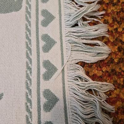 handmade green and white crochet blanket with a leaves pattern and fringed edges with a knitted reverse cat themed throw