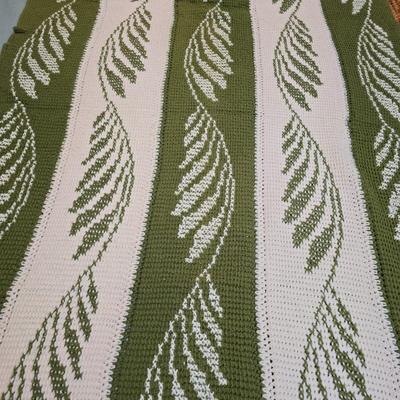 handmade green and white crochet blanket with a leaves pattern and fringed edges with a knitted reverse cat themed throw