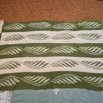 handmade green and white crochet blanket with a leaves pattern and fringed edges with a knitted reverse cat themed throw
