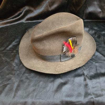 Bronzine felt Stetson Sutley fedora hat with a black grosgrain ribbon and feather accent. Size 7 1/4
