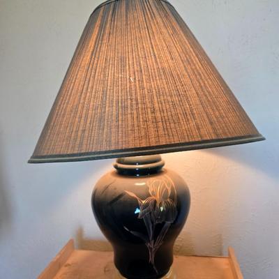 Small natural wood shelf with large ceramic lamp with an iris on it