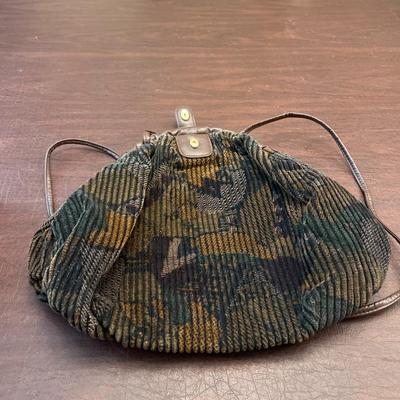 Sale Photo Thumbnail #141: Charming vintage corduroy and brown leather shoulder bag featuring a soft, textured plush corduroy body with an abstract earth-tone pattern. The bag has leather trim, a leather top flap with a snap closure, and a cinched drawstring-style construction. Int