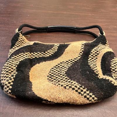 Sale Photo Thumbnail #144: Unique vintage Carpetbags of America shoulder bag featuring a bold black-and-tan woven wave pattern. This style is known for its durable tapestry construction and artisan-made quality.
The interior is lined with a natural canvas fabric and includes the or