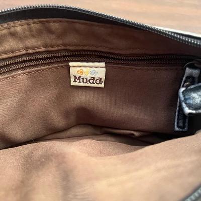 Sale Photo Thumbnail #150: Cute and compact Mudd brand crossbody purse featuring a black pebbled faux-leather exterior with a front buckle-detail pocket. The interior is clean, lined in brown fabric, and includes a zippered accessory pocket. Slim strap makes it perfect for hands-fr