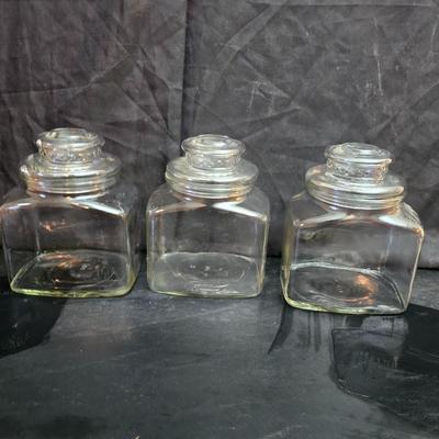 vintage 1981 Planters Mr. Peanut 75th Anniversary glass jar with three square glass apothecary jars, often used as kitchen canisters.