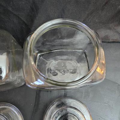 vintage 1981 Planters Mr. Peanut 75th Anniversary glass jar with three square glass apothecary jars, often used as kitchen canisters.