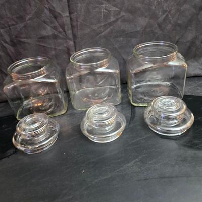 vintage 1981 Planters Mr. Peanut 75th Anniversary glass jar with three square glass apothecary jars, often used as kitchen canisters.