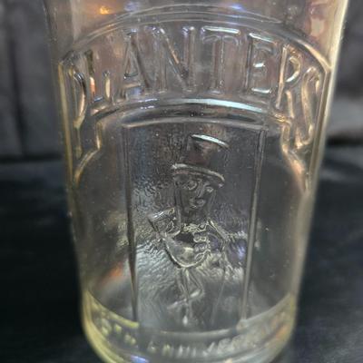 vintage 1981 Planters Mr. Peanut 75th Anniversary glass jar with three square glass apothecary jars, often used as kitchen canisters.