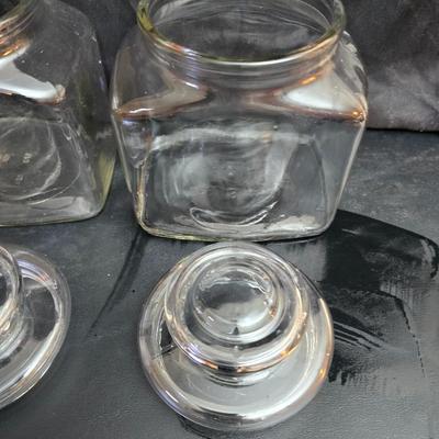 vintage 1981 Planters Mr. Peanut 75th Anniversary glass jar with three square glass apothecary jars, often used as kitchen canisters.