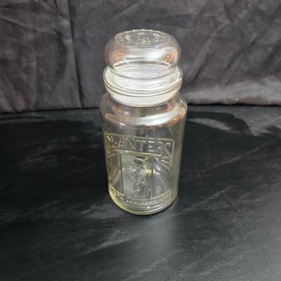 vintage 1981 Planters Mr. Peanut 75th Anniversary glass jar with three square glass apothecary jars, often used as kitchen canisters.