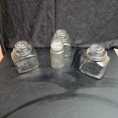 vintage 1981 Planters Mr. Peanut 75th Anniversary glass jar with three square glass apothecary jars, often used as kitchen canisters.