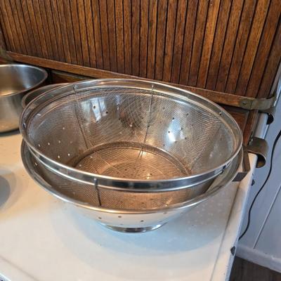 Stainless steel bowls and a strainer with an apron