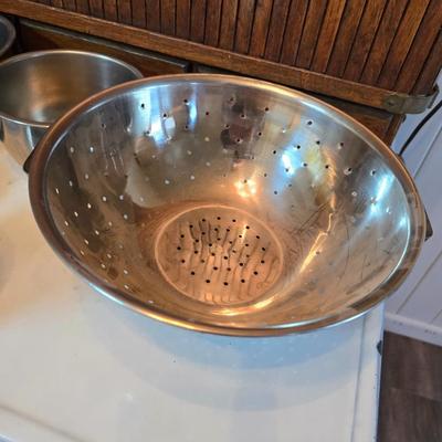 Stainless steel bowls and a strainer with an apron