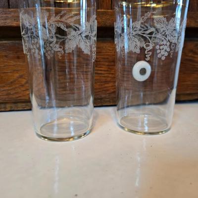 Two glass water pitchers and an assortment of miss-matched drinking glasses