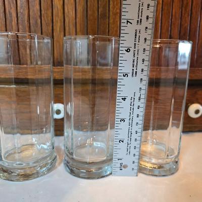 Two glass water pitchers and an assortment of miss-matched drinking glasses