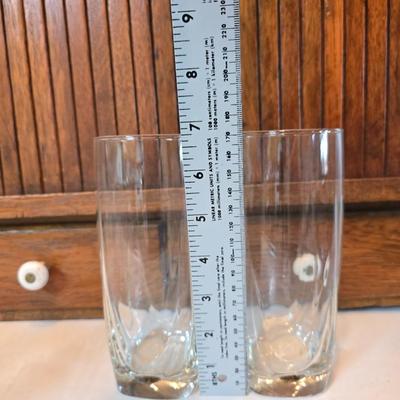 Two glass water pitchers and an assortment of miss-matched drinking glasses